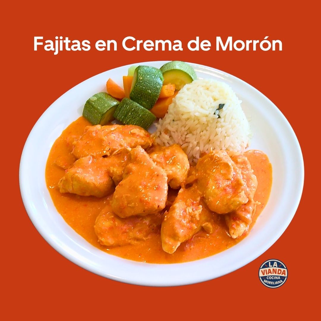 Fajitas en crema de morón: chicken in orange pepper cream sauce with rice and vegetables on a white plate.
